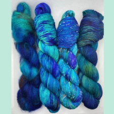 Four skeins on different bases in a bright blue green variegated colorway.