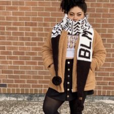 Long scarf that comes to tapered ends with large pom-poms. Colorwork says BLM at one end and has traditional African textile designs at the other.