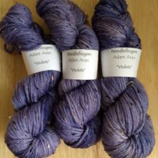 Three skeins of thick, tweed yarn in purple.