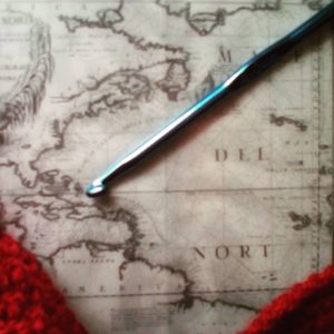 photo of an old map of the world, with a crochet hook on top of it