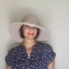 Smiling woman in wide brimmed hat.