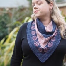 Small colorwork shawl with a tea rose motif in one of the v-shaped stripes.