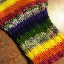 Self-striping yarn in rainbow colors with camo variegated stripes.