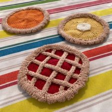 Round potholders that look like pie tops with lattice and berries, pumpkin, lemon, etc.