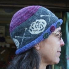 Rolled brim hat with colorwork band of yarn balls and crossed knitting needles.