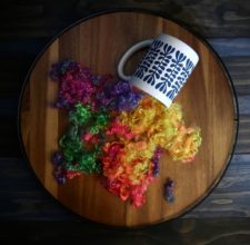 Rainbow hued locks spilling out of a coffee cup.