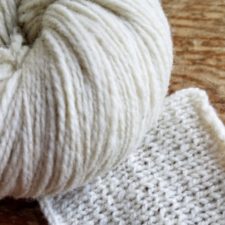 Swatch and ball of undyed yarn. Knits up a bit thick and thin.