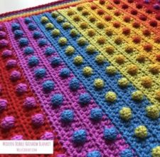 Rainbow striped baby blanket with contrasting bobbles every couple of inches.