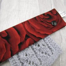 Fabric with vivid red roses is folded over a lace project.