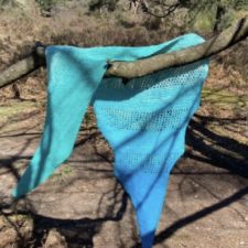 Shawl with solid and openwork stripes hangs over tree branch.