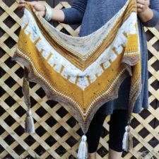Triangular shawl that has a scalloped edge ending in a deep point. Shawl has V-shape color and texture bands. Each point has a tassel.