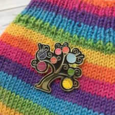 Enamel pin of balls of yarn as fruit on a tree.