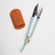 Snips with handles wrapped in colored thread, ending in a bead and tassel. Set includes leather cover for blades.