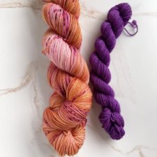 Pink base with variegation of gold and orange speckled with berry pink speckles. paired with bright mini purple skein