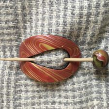 Red and gold modeling clay folded together to look like wood grain. Wooden stick pin has matching modeling clay ball.