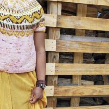 Woman in short sleeve sweater stands inside a barn. Sweater has colorwork yoke.