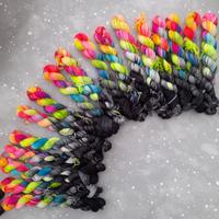 Array of skeins that are half tonal black and half neon rainbow.