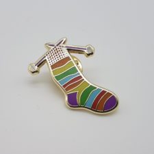 Enamel pin of knitting needles and a sock.