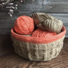 Knitted basket looks like old-fashioned bushel basket with contrasting top edge.