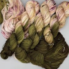 Variegated yarn in colors of pale roses and their leaves.