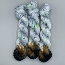 Three pale, speckled skeins dipped in deep earth colors at one end.