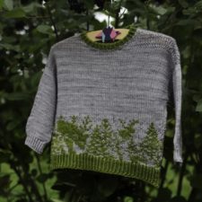 Long sleeve pullover with colorwork around the bottom of pines and animals.