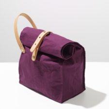 Fabric project sack with flat bottom. Rolled down top is secured with buckled leather strap, and at the side is a handle.