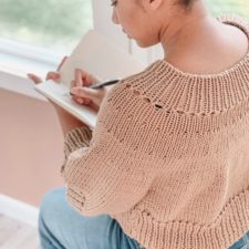 Knitted sweater with ribbed edges and yoke.