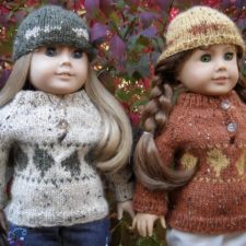 Two dolls wearing diamond-motif sweaters and hats.