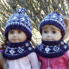 Two dolls wearing diamond-motif hats and buttoned cowls.