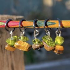 Five stitch markers made of a clear and an opaque polished stone.