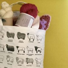 Tote bag full of yarn, with sheep breed drawings on the outside.