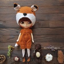 Big headed doll wearing knitted fox costume.