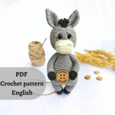 Crocheted donkey is holding a button.