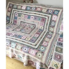 Borders of granny squares increasing in circumference form this beautiful blanket, shown in muted colors.