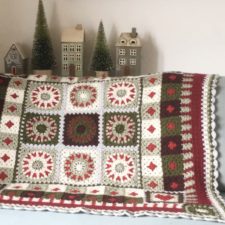 Wreaths set into squares, checks and various borders feature in this Christmas-theme throw.