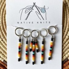 Five stitch markers with a line of beads descending from each. Row marker has three lines of beads.