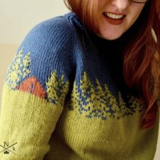 Colorwork sweater with tree silhouettes and a tiny cabin on the shoulder.