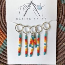 Five stitch markers with a line of beads descending from each. Row marker has three lines of beads.