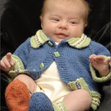 Baby in simple cardigan with contrasting color and trim, with matching booties