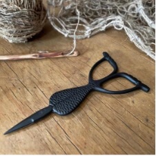 Matte black scissors where everything after the blade is shaped like a mermaid’s tail.