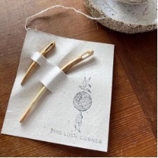 Two curved wood tapestry needles on a card.