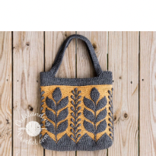 Crocheted tote in two colors with a raised vertical compound leaf pattern, alternating with another botanical vertical motif around the bag.