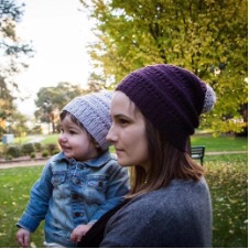 Woman and baby are wearing crocheted beanies with pom-poms.