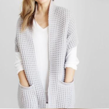 Long, no-closure cardigan in waffle texture. Sleeves are to the elbow. There are two large attached pockets along the front hem.