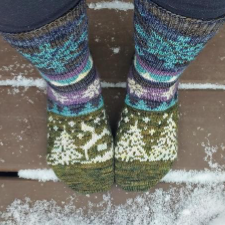 Socks of many colors. Designs are pine trees, a cabin and snowflakes.