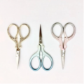 Ornate embroidery scissors in plain metal, and two colors with a pearlized finish.