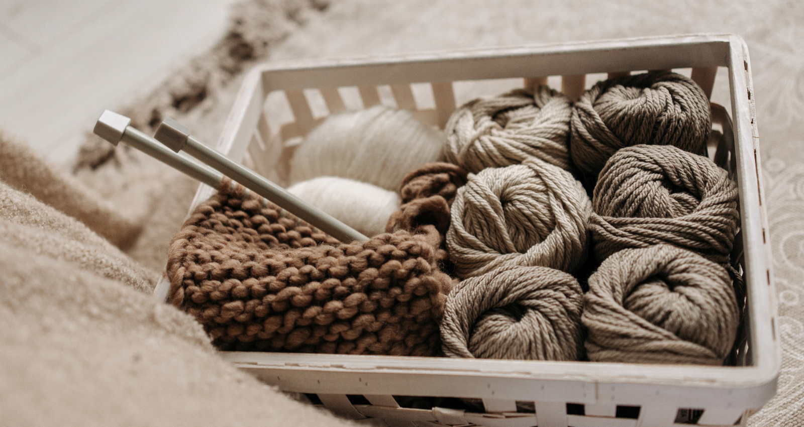 basket with balls of yarn, needles and the start of a knitting project.