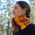Wide cowl with geometric colorwork in three warm colors.