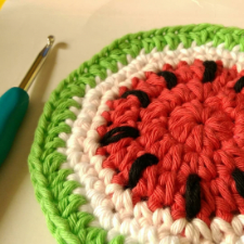 Round crocheted coasters that look like watermelon slices.